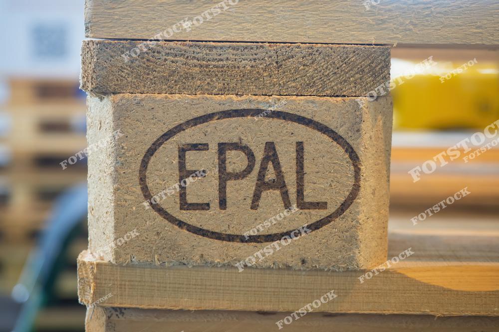 Фотография показывает деревянную палету с маркировкой EPAL, которая используется для хранения и транспортировки товаров. Поддоны EPAL являются стандартом для международных перевозок и хранения на складах. Это иллюстрация системы складирования и логистики с использованием стандартных контейнеров.